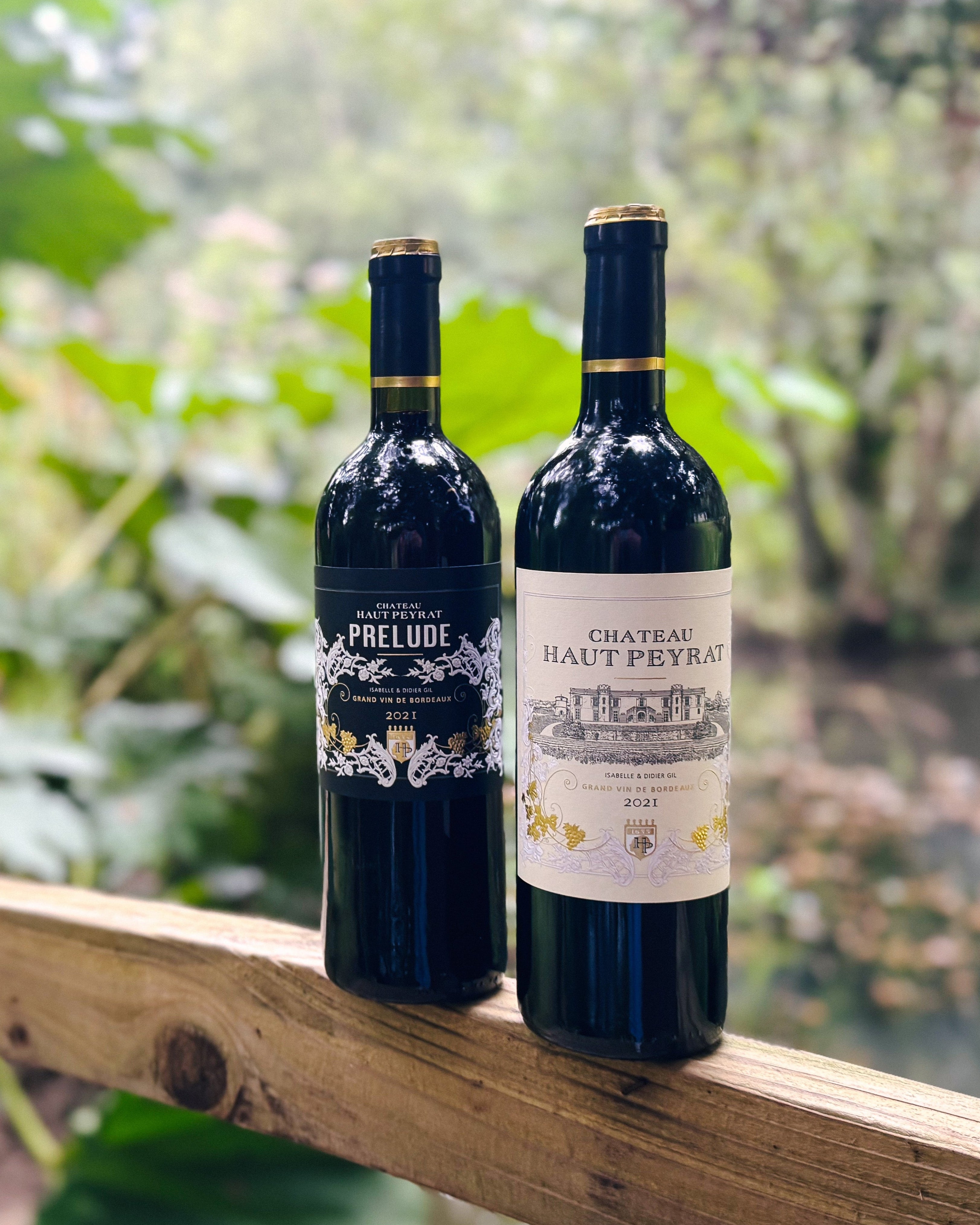 Two wine bottles on a wooden railing with a natural background