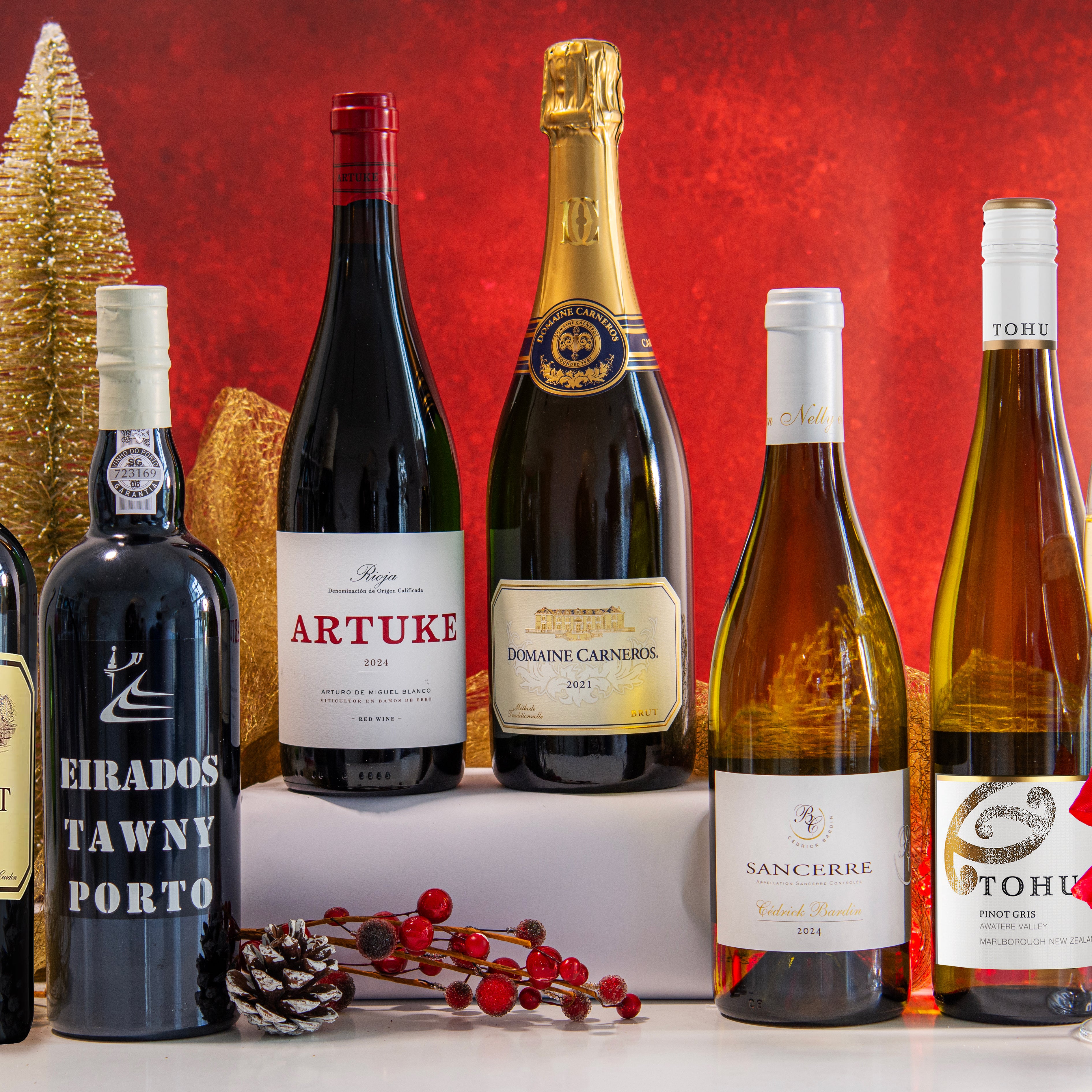 Assorted wine bottles on a red background with a glass of champagne.