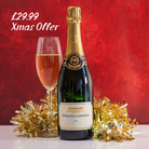 Bottle of Domine Carneros champagne with a glass and festive decorations on a red background
